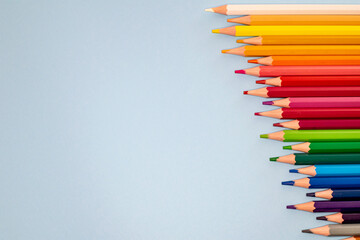 Fototapeta premium a selection of colourful wooden pencils lined up like a rainbow from dark to light