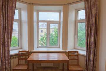 Home interior, three windows with access to the street, a table and two chairs