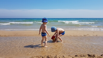 Two cute boys play on a deserted sandy beach