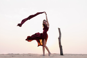 Silhouette of a girl in a red dress at sunset in the desert 