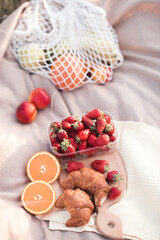Strawberry in box with croissants and fruits on cloth outdoors closeup. Holidays. Summer season.