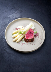 Barbecue dry aged wagyu beef fillet head medallion steak natural with white asparagus and sauce hollandaise as closeup on a modern design plate with copy space
