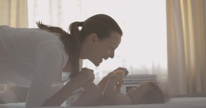 Mother changing baby's diaper in the bedroom smiling and talking to her child. 
