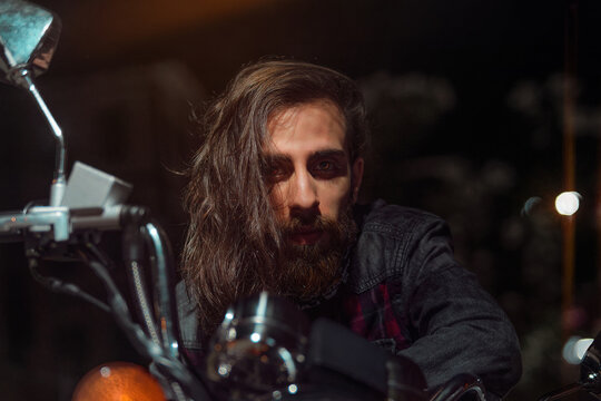 Night Street Portrait Of Young Guy With Long Hair On A Black Motorcycle