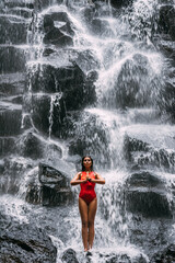Obraz premium A woman does yoga at a waterfall. Healthy lifestyle. The concentration of the body. A woman does yoga in Bali. A woman meditates in nature. Meditation at the waterfall. Young woman practicing yoga