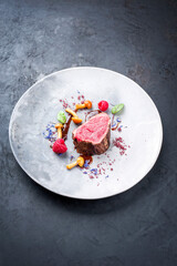 Barbecue dry aged wagyu beef fillet head medallion steak natural with forest fruits, mushrooms and hot chili sauce as top view on a modern design plate with copy space