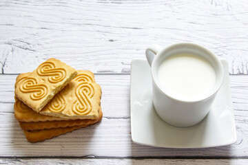 Cookies stacked and a cup of milk on a wooden background. Healthy snack.