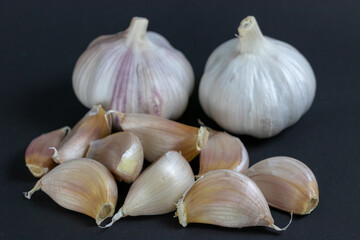 Whole and loose garlic spice on dark background