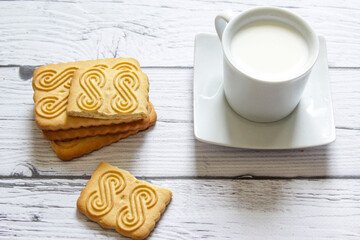 Cup of milk and cookie on a wooden background. Healthy breakfast.