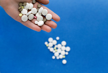 Pills on the palm on a bright blue background. Healthcare, medecine, treatment, therapy concept.