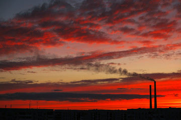 Colorful Magic Sunset. Roofs of city houses during sunrise. Dark smoke coming from the thermal power plant pipe.