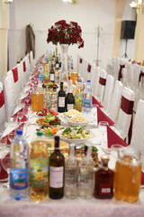 Wedding room with a table decorated with food, drinks, flowers.