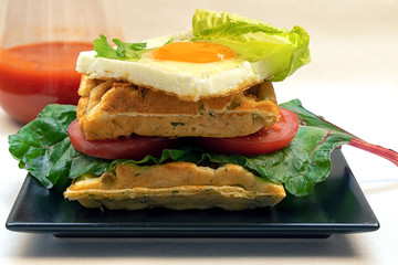 A rich breakfast of eggs with vegetables and lush waffles with cheese and greens
