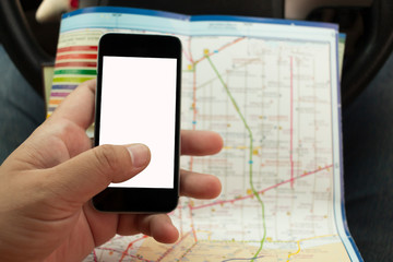 Mobile phone in hand with white isolate screen and blurred paper map.