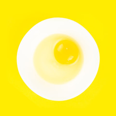 Raw egg in bowl isolated on yellow background. Healthy food and cooking at home concept.