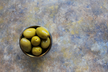 Bowl of olives on a variegated blue background. Food frame. Top view. Copy space.