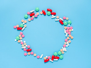 Frame of colorful pills tablets on blue background. Health care. Treatment.