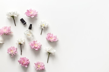 Flat lay composition with spring flowers and perfume jar on white background. Top view, flat lay