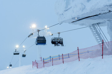 People on ski lift in winter resort - Holidays, snow gear renting, skiing, snowboarding and...