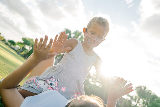 Mom and daughter in protective masks against coronavirus. in the park in sunny weather on a background of green grass.