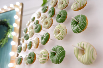 Sweet fresh donuts at a festive wedding vertical buffet. Concept of modern party decoration.