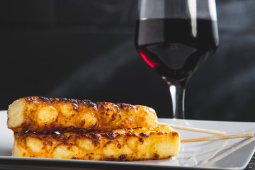 Espetinhos assados de queijo servido em prato no boteco com taça de vinho