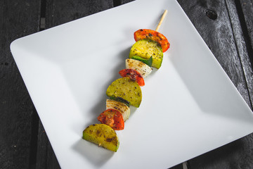 Espetinho assado de legumes servido em prato no boteco