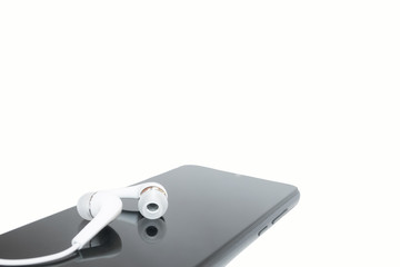 A pair of white headphones lying on the smartphone close-up.Isolated on a white background.