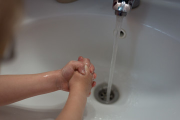 kid washing hands with soap over sink in bathroom, closeup