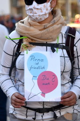 Schild in der Hand einer Demonstrantin mit Mundschutz: 