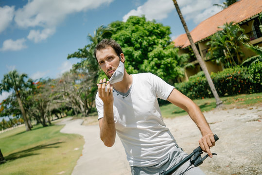 a man cyclist with a beard and a mask. mask against the virus coronavirus codiv-19. in a white tank top on a bike.