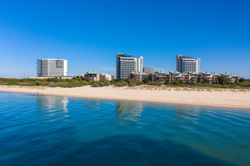 Landscape View of the perfect white sandy beach with breaking waves. Transparent sea water. Paradise and desert beach in Troia, Setubal, Portugal. Arrabida mountain in the background