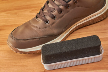 shoe brush cleans cream leather sneakers on a wooden parquet