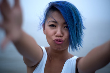Woman in white dress and funky blue hair grabs cameraman for a kiss