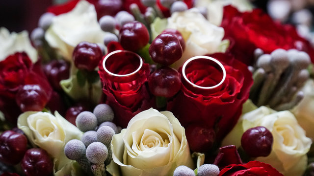 Bouquet of red and white roses and rings on flowers.