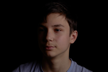 Obraz premium Portrait of a teenager on a black background. The boy has dark hair