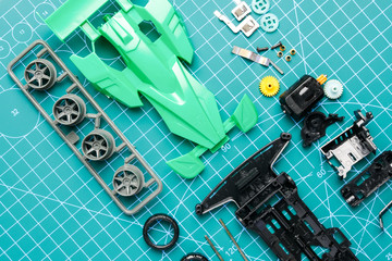 Flatlay mini 4WD toy cara awaiting to be assemble on cutting mat. Popular toy car during 90's.