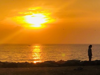 silhouette of a man walking on the beach at sunset