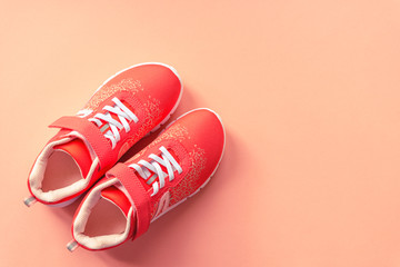Orange sneakers on coral pink background. Concept of healthy life, sport and training