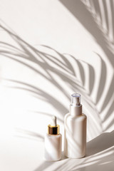 Fototapeta Cosmetic tonic and serum in blank packages on a background of white wall with palm leaves shadows. Natural skincare products concept. obraz
