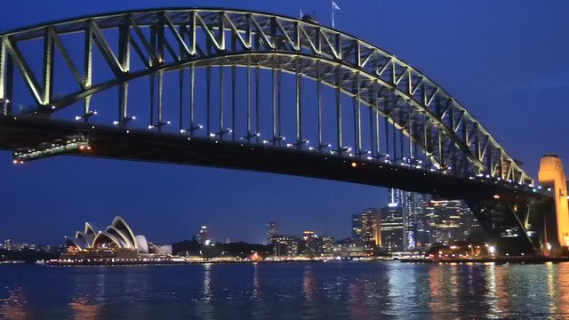 The Sydney Harbour bridge at sunset with bright illumination in slow panning to The Rocks.
