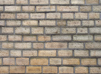 a full frame image of an old yellow sandstone wall made of regular blocks