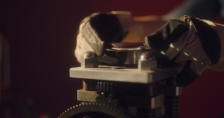 Worker in gloves is twisting some valve using two hands