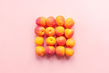 Fototapeta na wymiar Ripe apricots piled on the table, top view, flat lay. Pink background