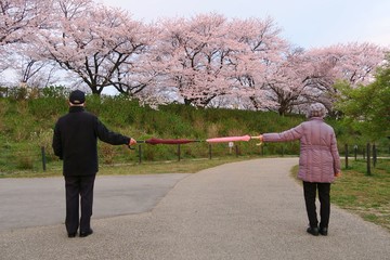 Social distancing. A good example of social distancing to avoid the spread of coronavirus (COVID-19). Two people (a man and a woman) stand apart holding two umbrellas.