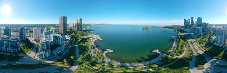 Fototapeta na wymiar Artistic creative view of Humber Bay Shores Park city view and green space with skyline cityscape, azure lake Ontario. Skyscrapers over The Queensway on sunset at summer, Etobicoke, Ontario, Canada