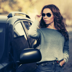 Young fashion woman in sunglasses standing next to her car