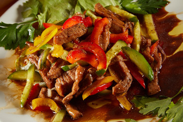 Menu of gastronomic restaurant. Hot salad with veal meat and vegetables with sweet sauce on the white plate. Top View. Grilled meat with salad on a white plate on wooden background.