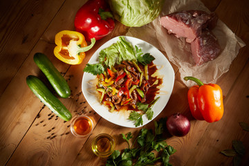 Menu of gastronomic restaurant. Hot salad with veal meat and vegetables with sweet sauce on the white plate. Top View. Grilled meat with salad on a white plate on wooden background.