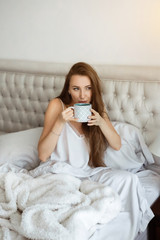 Home self isolation, bedtime. People adaptation during covid-19 pandemic quarantine. Girl in bed, drinks coffee